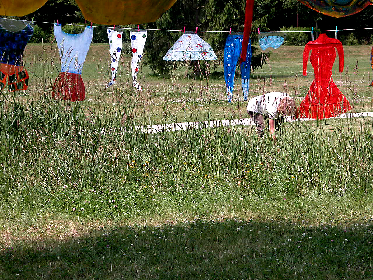 Habits en papier suspendus sur une corde passant entre les arbres